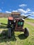 Agricultural red tractor with trailer. Faded paint, retro.