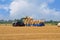 Agricultural scene, tractor loads the bales of hay on the trailer.