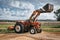 Agricultural tractor with digger and ploughing attachment to till the ground in a field