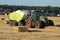 Agricultural tractor pulling an automatic hay baler and baling straw