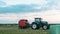 Agricultural work in a field at sunset. Equipment for forage. Film wrapping system. Round bales of feed for farm animals