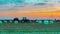 Agricultural work in a field at sunset. Equipment for forage. Film wrapping system. Round bales of feed for farm animals