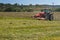 Agricultural work. Red tractor mowing the meadow, Czech Republic. Farmer harvested hay.