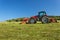 Agricultural work. Red tractor mowing the meadow, Czech Republic. Farmer harvested hay.