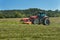 Agricultural work. Red tractor mowing the meadow, Czech Republic. Farmer harvested hay.