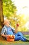 Agricultural worker with basket of apples sitting in orchard and