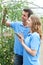 Agricultural Workers Checking Tomato Plants Using Digital Tablet