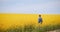 Agriculture - Farmer or Agronomist Walking on Agricultural Field and Looking at Rapeseed Yellow Flowers Crops.