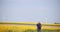 Agriculture - Farmer or Agronomist Walking on Agricultural Field and Looking at Rapeseed Yellow Flowers Crops.