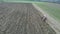 Agriculture and farming - Tractor plough a field in early spring aerial footage