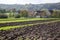 Agriculture scenery with partly ploughed field in front of farm house and barn