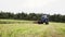 Agriculture tractor riding cutting grass field at farm near forest