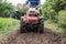 Agriculturist controlling hand tractor plowing on soil field in plantation. Agribusiness preparing cultivated land for sowing