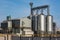 Agro silos granary elevator in winter day in snowy field. Silos on agro-processing manufacturing plant for processing drying