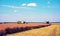 Agroindustrial industrial landscape with combine harvesters picking up hay on a field on a sunny day against a background of