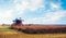 Agroindustrial industrial landscape with combine harvesters picking up hay on a rape field on a sunny day against a background of