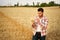 Agronomist examining cereal crop before harvesting sitting in golden field. Smiling farmer holding a bunch of ripe