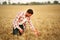 Agronomist examining cereal crop before harvesting sitting in golden field. Smiling farmer holding a bunch of ripe