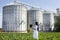 Agronomist with laptop with silos behind