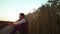 Agronomist observing wheat field husbandry at golden sunset alone portrait.