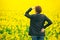 Agronomist standing in field of blooming cultivated rapese