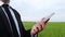 Agronomist uses a white tablet on a background of green wheat field