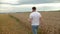 Agronomist in white t-shirt and jeans walking in wheat field.