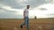 Agronomist in white t-shirt and jeans walking in wheat field.