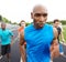 Ahead of the pack. Cropped front view of a focused male athlete with competitors in the background.