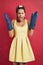 Ahhh, more chores. Studio shot of a young woman wearing oven mitts against a red background.