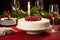 AI generated. Christmas cake glazed and decorated with white cream and sugared cranberries on festive red table