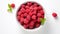 AI generated illustration of a bowl of raspberries on a white background