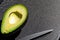 AI generated illustration of a cut avocado on a cutting board with a knife