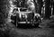 AI generated illustration of an old car parked in a pathway in a forest in grayscale