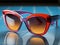 AI generated illustration of a pair of colorful sunglasses resting on a blue surface