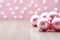 AI generated. Pink Christmas balls on a light wooden background with festive blurred bokeh background