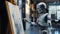 An AI robot paints with a brush on an easel. Realistic humanoid artist robot draws on the canva. Futuristic technology