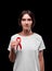 AIDS, awareness concept. A brunette female holding a red ribbon on a black background. Solidarity with people with AIDS.