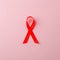 AIDS awareness red ribbon on pink background. world aids day concept, symbol of human immunodeficiency virus disease