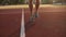 Aimed close up footage of man`s legs jumping over the skipping rope on track at stadium outdoors . Wearing blue sneakers