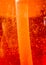 Air bubbles within orange dishwashing liquid with plastic tube inside. Abstract ember background.