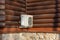 Air compressor, external split wall type of outdoor home air conditioner unit installed on the wall of a country wooden log