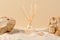 Air freshener on a natural background with sand, stones and shells. Perfume composition in a glass diffuser with reed sticks. Home