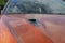 Air intake on the hood of an orange sports car.