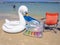 An air mattress, a life preserver and a red beach chair by the sea on a warm sunny day.