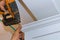 Air nailer tool carpenter using nail gun to crown moldings on kitchen cabinets with white cabinets