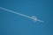 air plane condensation flying in front of the moon on blue sky background