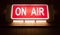 On Air sign icon glowing on the wooden wall of sound recording studios, live broadcast radio production room