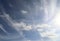 Aircraft condensation contrails in the blue sky inbetween some clouds