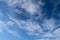 Aircraft condensation contrails in the blue sky inbetween some clouds